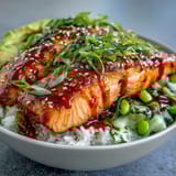 A close-up of Honey Sriracha Salmon Bowl with glazed salmon, edamame, and creamy avocado.
