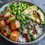 Flaky baked salmon cubes glisten atop fluffy jasmine rice in this vibrant salmon rice bowl, with edamame and creamy avocado slices.