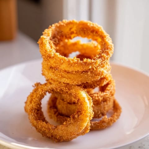 A close-up of perfectly battered and golden-brown onion rings, cooked to perfection.