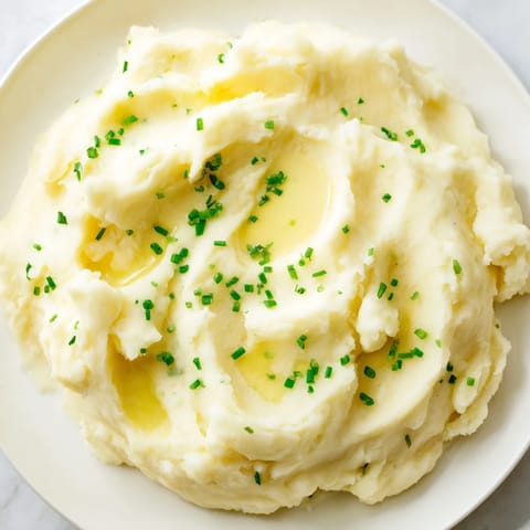 A steaming bowl of creamy mashed potatoes, topped with fresh herbs, a classic American side.