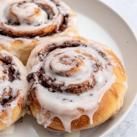 Sweet American cinnamon rolls, fresh from the oven, glistening with a generous layer of icing.