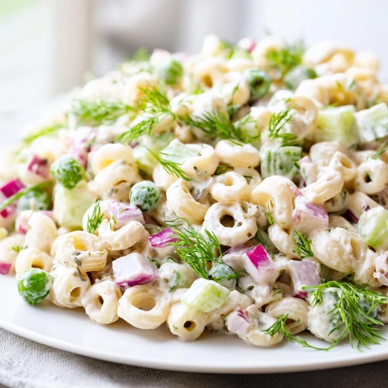 Vibrant bowl of creamy dill pickle pasta salad featuring ditalini and fresh herbs, ideal for a vegetarian side dish at any picnic.