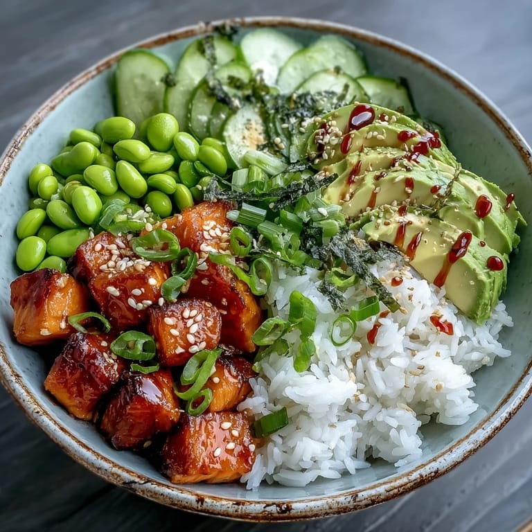A close-up of the salmon rice bowl shows crisp cucumber rounds, green edamame, and a drizzle of spicy sriracha mayo over the salmon.