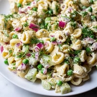 Creamy Dill Pickle Pasta Salad served chilled in a white bowl, garnished with fresh dill and red onion, perfect for a summer potluck.