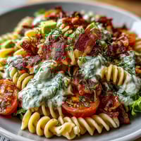 A vibrant summer BLT pasta with avocado ranch dressing, topped with crispy bacon and fresh cherry tomatoes.  